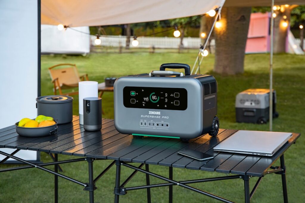 Portable power stations powering electronics, lighting, and a cooler at a campsite.